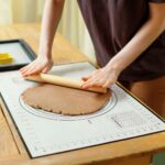 Mann rollt Teig auf Brett aus