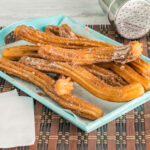 Churros auf einem Blech mit Puderzucker