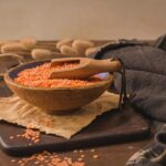 Rote Linsen in Schüssel mit Holzlöffel