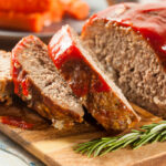 Hackbraten mit Tomatensauce und Thymian auf einem Holztablett