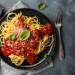 Spaghetti mit Tomatensauce auf einem Teller mit Basilikum und Parmesan