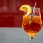 Aperol Spritz in Weinglas mit Strohhalm und Zitrone